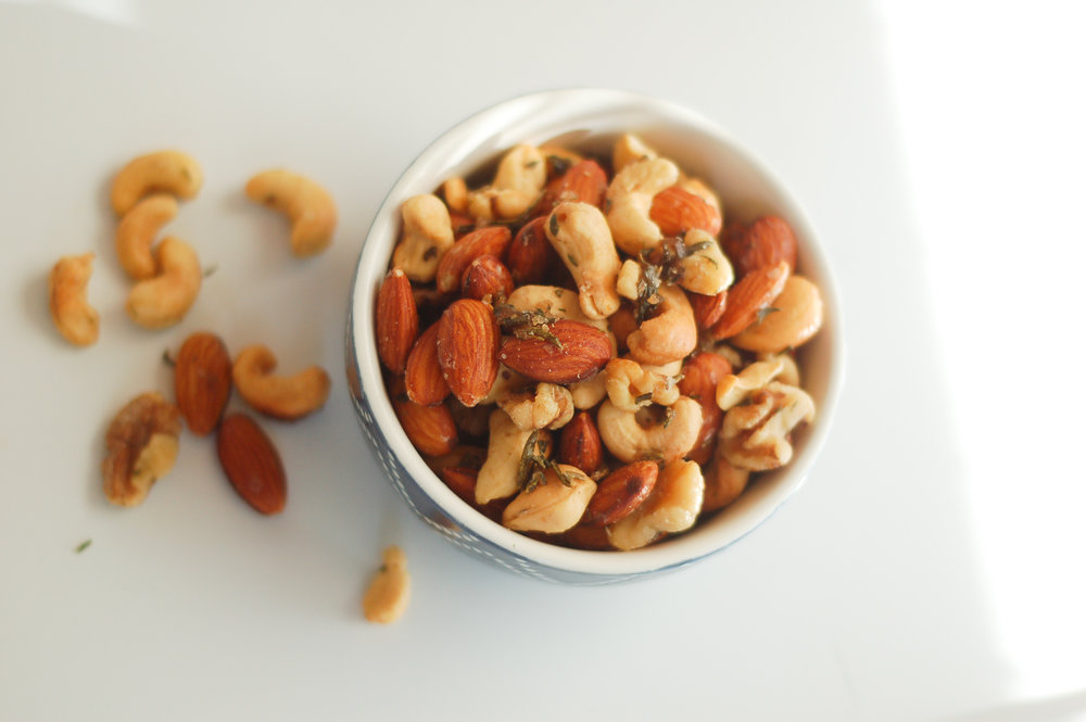 pistachios, almonds, and herbs in a white bowl