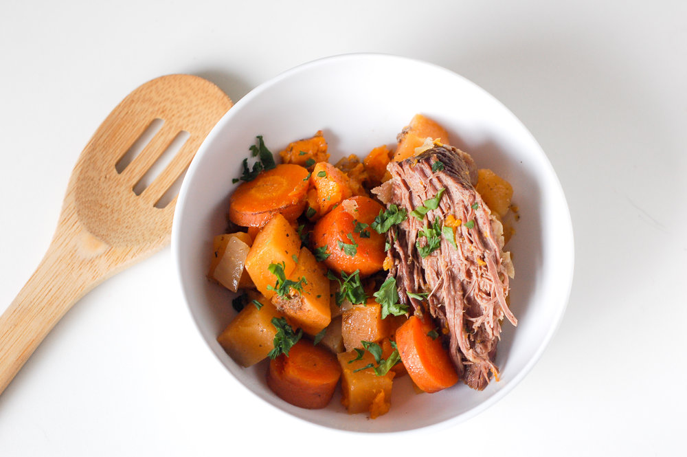 delicious pot roast in a white bowl with sweet potato and carrots