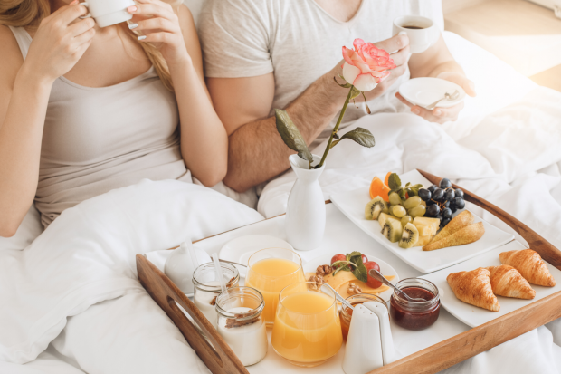 couple laying in bed sipping coffee at a hotel 