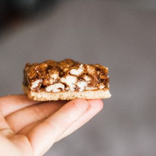 paleo pecan pie bars being held in a person's hand